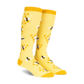 Pair of yellow knee-high socks with a pattern of black and white bees on honeycombs. 