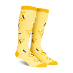 Pair of yellow knee-high socks with a pattern of black and white bees on honeycombs. 