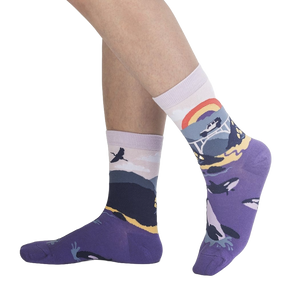 A pair of purple calf socks with a colorful pattern of mountains, flowers, and a rainbow on a black background.