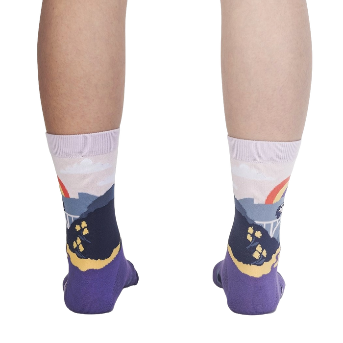 A pair of purple calf socks with a colorful pattern of mountains, flowers, and a rainbow on a black background.