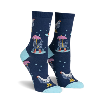 front view of a pair of women's socks with a navy blue background. the socks have a repeating pattern of white chickens with pink umbrellas and yellow rainboots. there are white raindrops scattered across the sock. the socks have a light blue trim at the top.