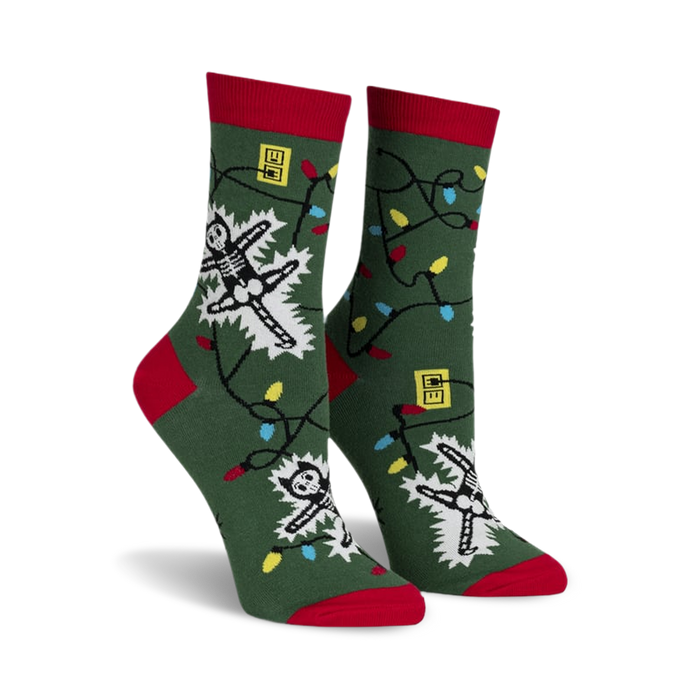 front view of a pair of green socks with christmas lights and a skeleton getting electrocuted. the socks have red cuffs.