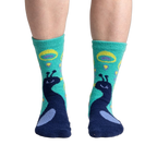 Close-up shot of 'I'm Your Biggest Fan' slipper socks on a person's feet, showcasing the teal and navy peacock design.