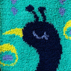 Detailed close-up of the peacock's face on the fuzzy slipper socks. 
