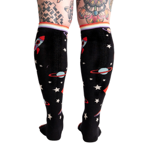 A pair of black knee-high socks with a pattern of rockets, planets, and stars in bright colors.