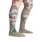 Lifestyle shot showcasing Orchid knee-high socks on a model with tattoos, highlighting the socks' length and design.