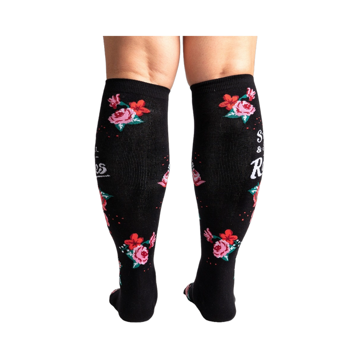 Rear view of black knee-high socks with a rose pattern and text.