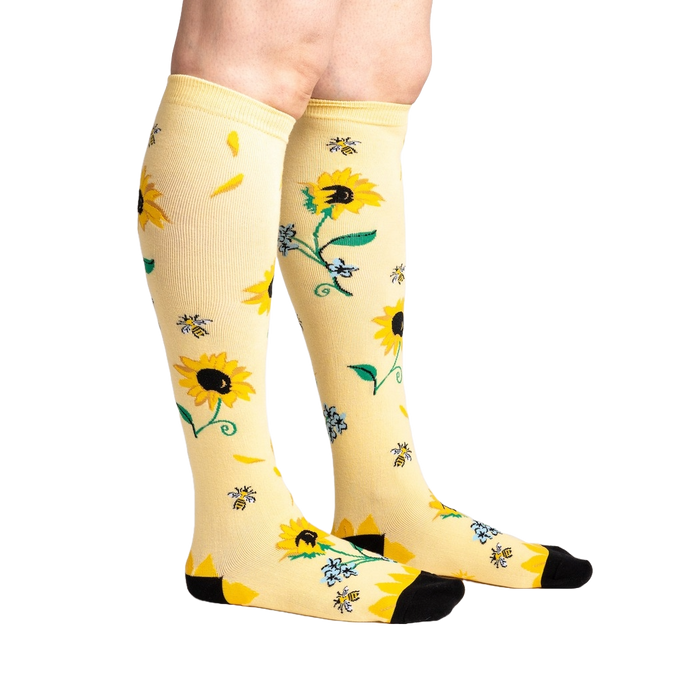 Yellow knee-high socks with a pattern of sunflowers, bees, and blue flowers.