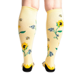 Rear view of the socks on a person's legs, showcasing the back of the sunflower design.