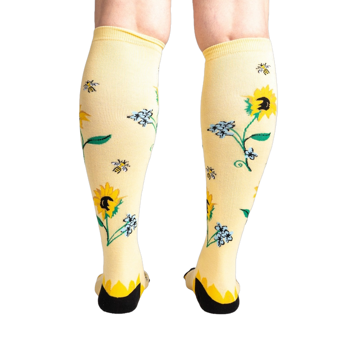 Rear view of the socks on a person's legs, showcasing the back of the sunflower design.