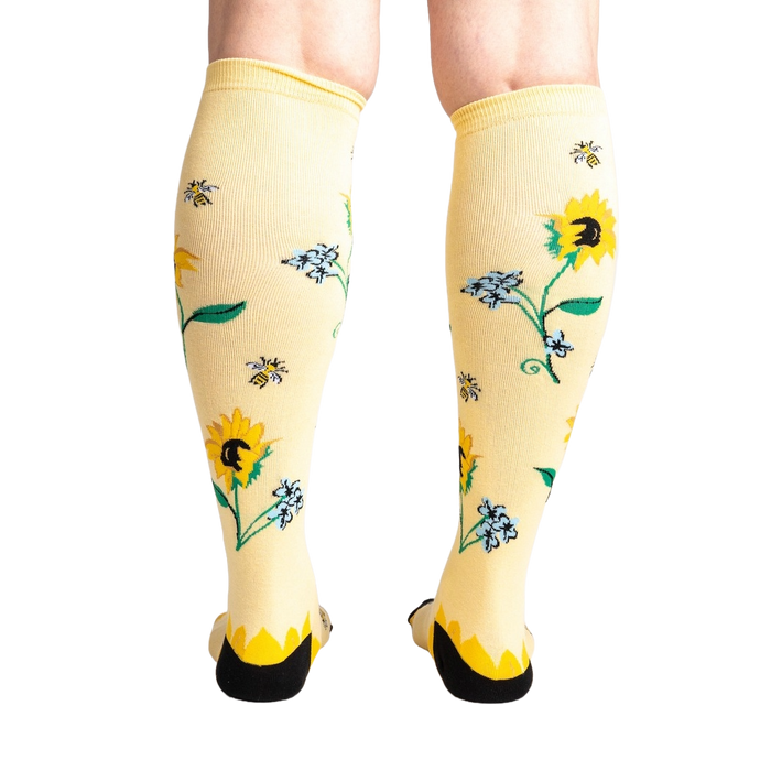 Yellow knee-high socks with a pattern of sunflowers, bees, and blue flowers.