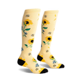 Pair of knee-high socks in pale yellow with a sunflower, bee, and floral design. Black heel and toe.