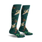Pair of women's knee-high socks in hunter green. Features gold cranes, red blossoms, and green foliage.