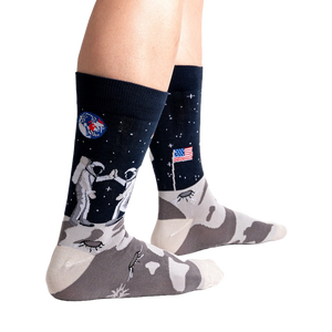 A pair of black socks with an astronaut on the moon design.
