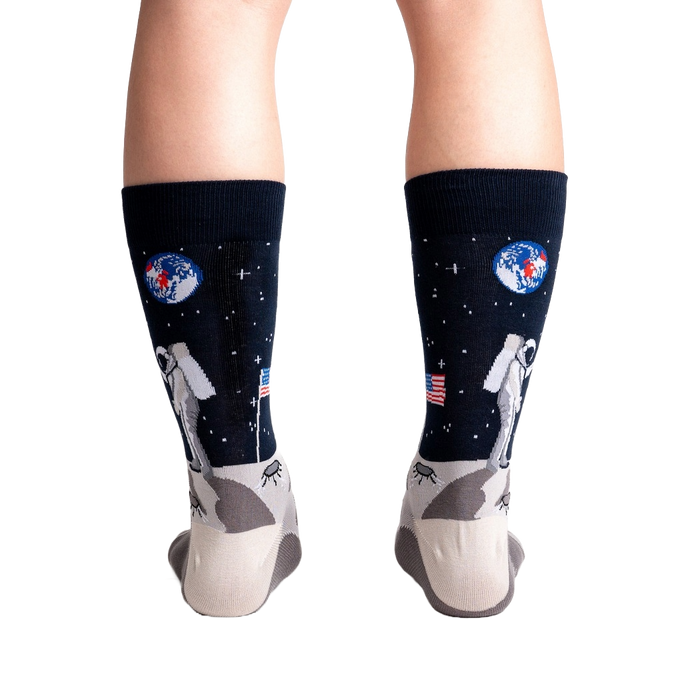 A pair of black socks with an astronaut on the moon design.