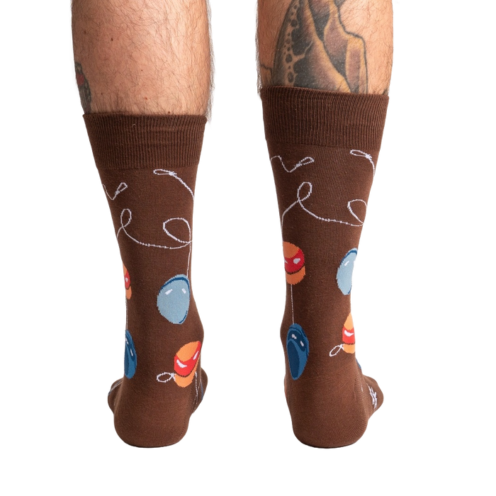 A pair of brown socks with a pattern of red, blue, and yellow balloons on them.
