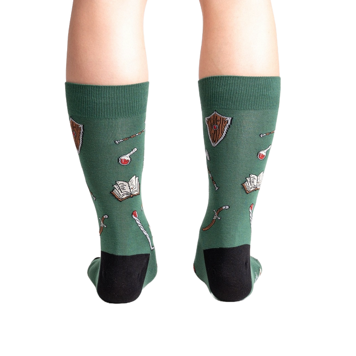 A pair of green socks with a pattern of swords, shields, books, potions, and other fantasy-themed items.