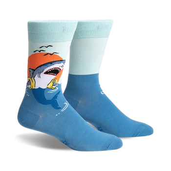 men's blue crew s.o.s. socks with a playful pattern of sharks sporting life preservers swimming in the ocean at sunset.   