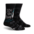 Pair of black crew socks featuring the text of the US Constitution preamble in teal and gray. A quill and ink design is subtly present.