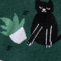 Close-up of a section of the sock showing a black cat and a stack of books.
