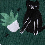 Close-up of a section of the sock showing a black cat and a stack of books.