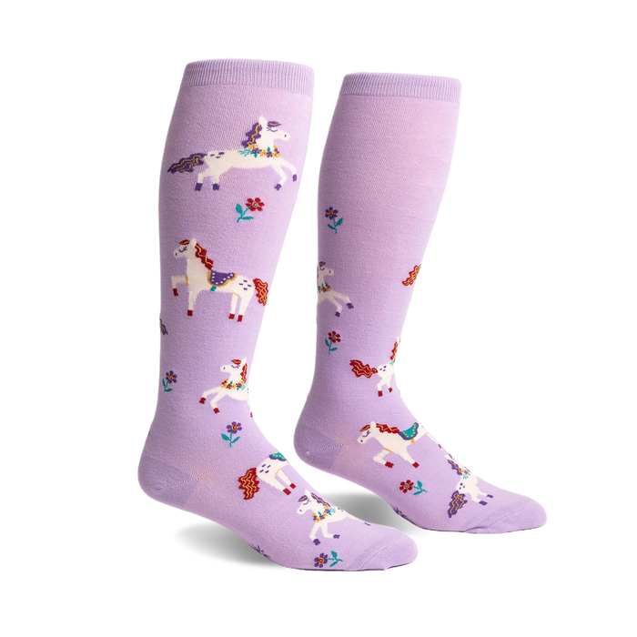 Pair of lavender knee-high socks with a whimsical design of prancing white unicorns and small flowers.