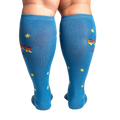 Rear view of model wearing blue knee-high socks featuring 'Queer Joy' in rainbow and yellow stars.