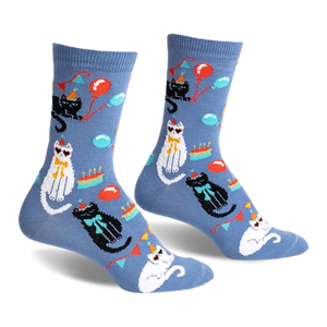 front view of a pair of socks with a blue background and cats wearing party hats. there are also balloons and cake on the socks.