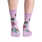 Lifestyle shot of model wearing a pair of lavender crew socks with turtles and donuts.