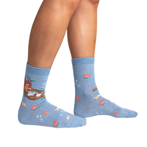A pair of blue socks with a pattern of cartoon sea otters wearing flower leis.