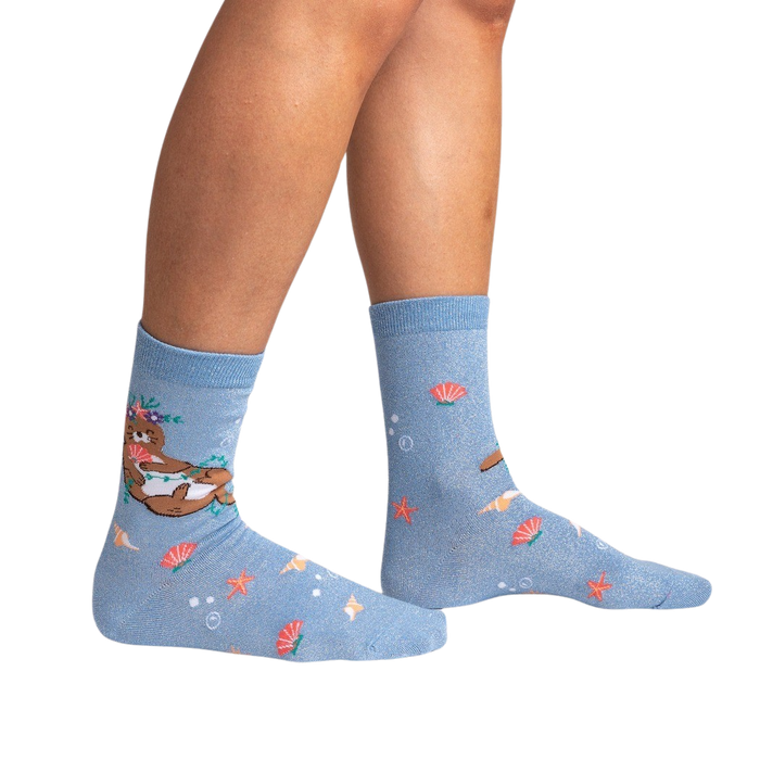 A pair of blue socks with a pattern of cartoon sea otters wearing flower leis.