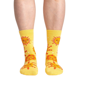 A pair of yellow socks with a pattern of red and orange suns with smiley faces.