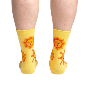 A pair of yellow socks with a pattern of red and orange suns with smiley faces.