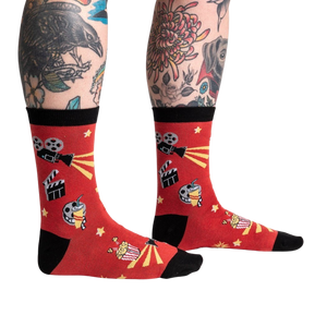 A pair of red socks with black toes and heels. The socks have a pattern of cartoon movie cameras and yellow stars.