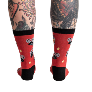 A pair of red socks with black toes and heels. The socks have a pattern of cartoon movie cameras and yellow stars.