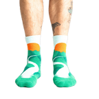 Lifestyle shot of a person's legs wearing the teal and light blue mountain slipper socks.