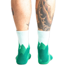 Back view of a person's legs wearing the teal and light blue mountain slipper socks, showcasing the non-slip soles.