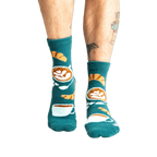 Lifestyle shot of model wearing teal blue coffee and croissant slipper socks.