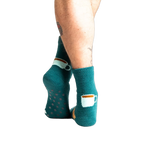Back view of model wearing teal blue coffee and croissant slipper socks.
