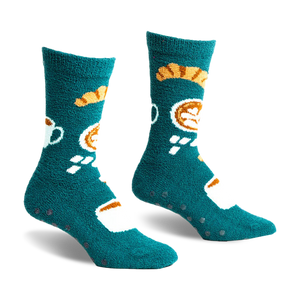 pair of teal fuzzy socks with a coffee cup and pastry design. the socks have black grippers on the bottom.  the socks are laying flat on a white background.  they are viewed from the front.