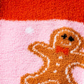 Detailed close-up of the gingerbread man design on the pink fuzzy socks.