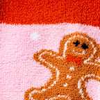 Detailed close-up of the gingerbread man design on the pink fuzzy socks.