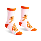 Pair of pink fuzzy slipper socks with orange cuffs. Gingerbread men and houses are embroidered on the socks.