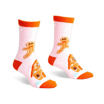 Pair of pink fuzzy slipper socks with orange cuffs. Gingerbread men and houses are embroidered on the socks.