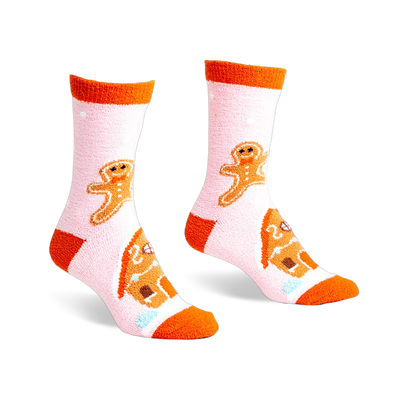 Pair of pink fuzzy slipper socks with orange cuffs. Gingerbread men and houses are embroidered on the socks.