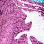 Close-up detail shot of the soft, purple fabric and white unicorn graphic.