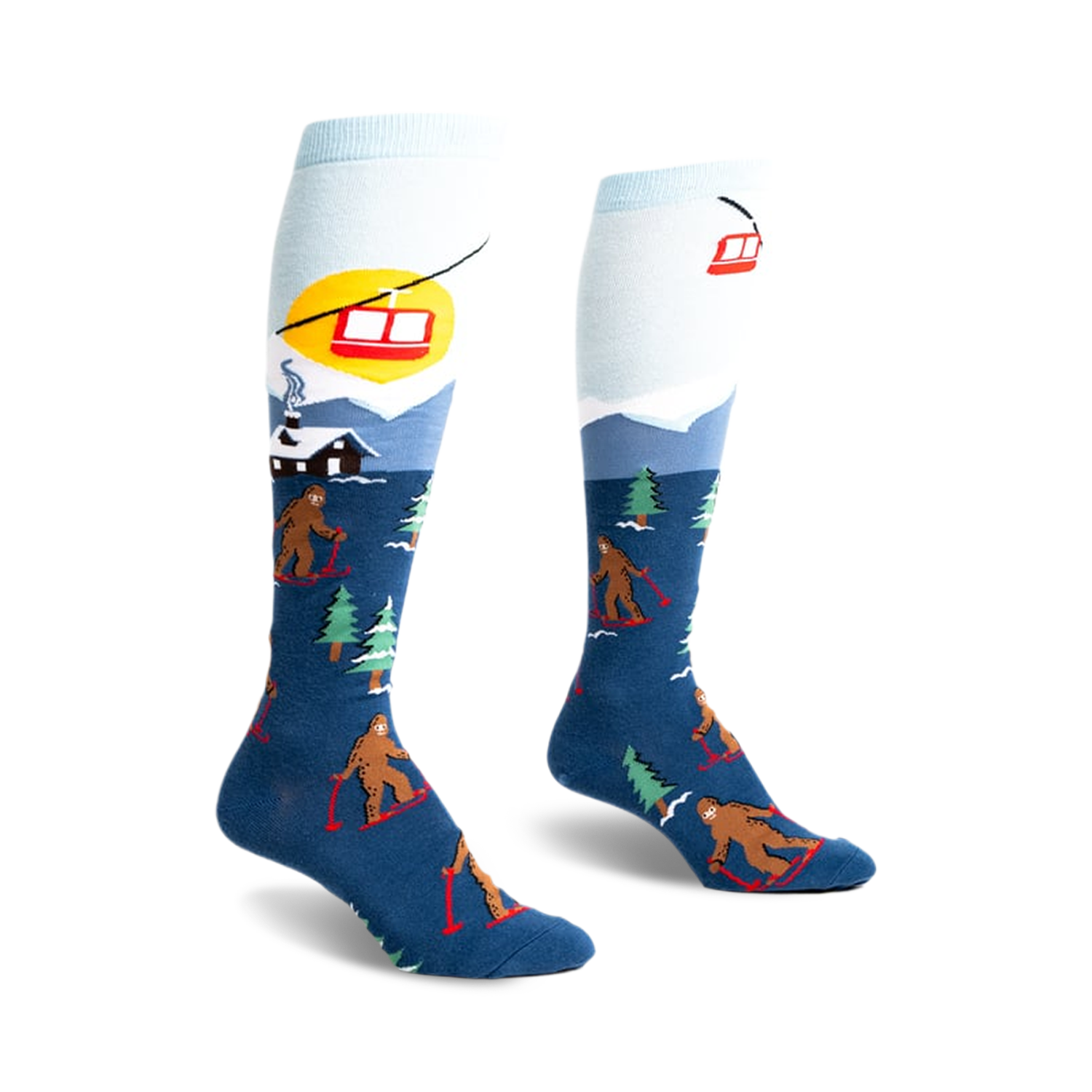 Pair of blue and light blue knee-high socks. Design features Bigfoot skiing, a snowy mountain scene, and a ski lift.