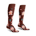 Pair of brown knee-high socks with a whimsical pattern of gingerbread houses, candy canes, and small pine trees.
