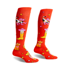 Pair of orange knee-high socks with a fun design of cats wearing cowboy hats and boots.  Stars and cacti are also featured.