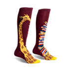 Pair of burgundy knee-high socks. One sock has a giraffe's neck & head; the other, a stack of colorful books.